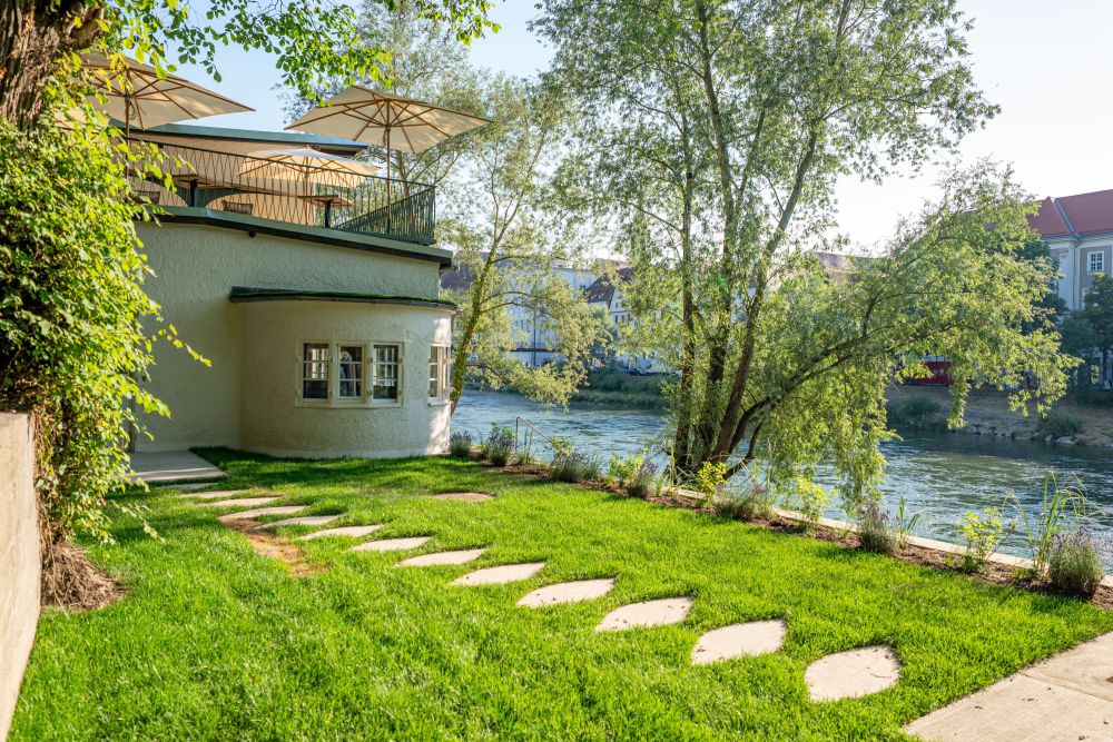 Außenansicht vom hauseigenen Garten mit Blick auf die Wiese, einen Teil des Hauses und die Enns mit gegenüberliegendem Ufer – ARKFORM