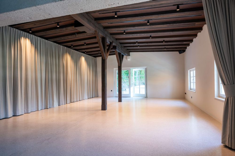 Innenansicht Eventraum mit historischer Holzdecke und Stützsäulen, Vorhänge dienen zur Raumteilung – ARKFORM